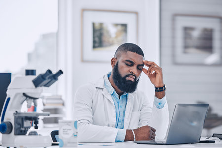 Headache, stress and man with burnout from science, research mistake or laptop error in laboratory. Tired, sad or frustrated african scientist with migraine pain, anxiety and fatigue of mental healthの写真素材