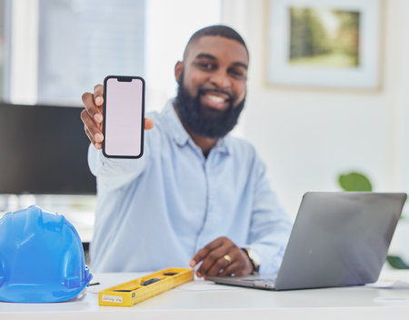 Black man, engineer or phone mockup in office for communication, construction update or networking. Smile, screen or portrait of happy architect on mobile app display or mock up space on Internetの写真素材
