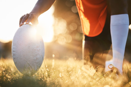 Rugby, ball closeup and sun, sports on field outdoor with bokeh, target with fitness and train for match. Exercise, athlete person hand and game with practice, health and active with player and readyの写真素材