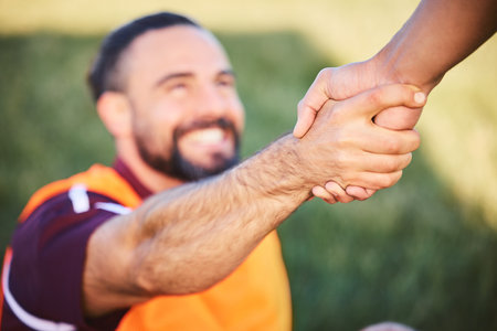Hands, rugby and teamwork with a man helping a friend while training together on a stadium field for fitness. Sports, exercise and team building with an athlete and teammate outdoor for supportの写真素材