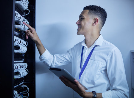 Man, electrician and tablet in server room or data center inspection, system solution or cybersecurity management. Engineering person on digital technology by power cables, electricity or programmingの写真素材