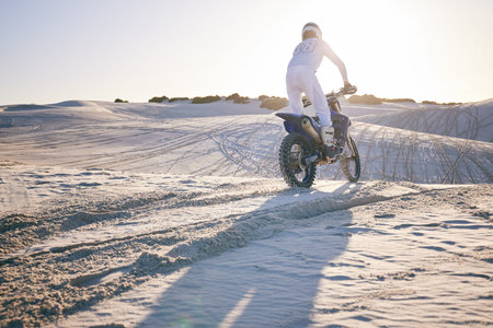 Desert, motorbike and back of sports person travel, transport and driving on challenge adventure, freedom and training. Nature sunset, extreme action and athlete ride motorcycle on sand dunes hillの写真素材