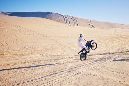 Bike, sports and space with a man in the desert for adrenaline, adventure or training in nature. Moto, fitness and freedom with an athlete riding a motorcycle for energy or balance on sand in Dubaiの写真素材