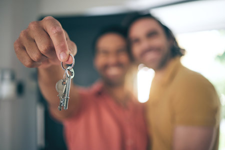 Hand holding, keys and gay couple smile for real estate, success or new home celebration. Property, dream or lgbt men embrace with love, smile or excited for moving, apartment or mortgage loanの写真素材