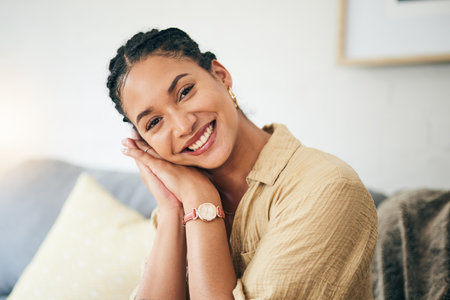 Portrait, smile and woman on home sofa to relax in living room apartment. Face, happy and person or girl on couch in lounge in Brazil, positive or cheerful, confident or peace in house in the morningの写真素材