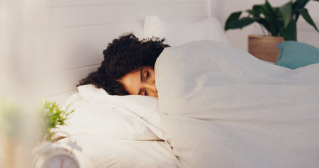 Woman, bed and insomnia anxiety or restless for sleep or rest in home bedroom with fatigue or stress. Female person frustrated with sleeping problem, depression or disorder while dreaming or sleeplesの写真素材