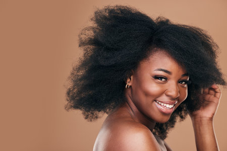 Portrait, hair care and black woman with smile, beauty and wellness on a brown studio background. Mockup space, person and model with texture, afro and natural with aesthetic, makeup and cosmeticsの写真素材