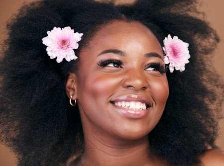 Hair care, flowers and black woman in afro, thinking and beauty in studio isolated on brown background. Smile, floral hairstyle cosmetic and natural African model in organic salon skincare treatmentの写真素材