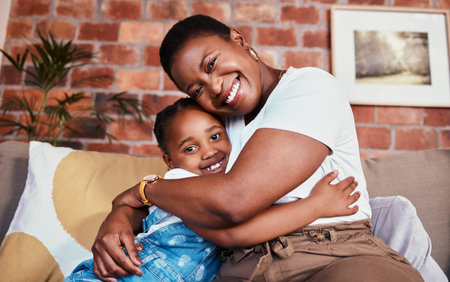 Portrait, mother and daughter on sofa with hug, smile and relax bonding in living room together....