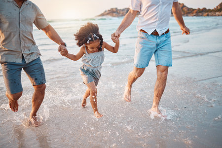 Beach, running and parents holding hands with girl in water on holiday, vacation and adventure. Lgbtq family, summer and happy child with fathers by ocean for bonding, relationship and fun outdoorsの写真素材