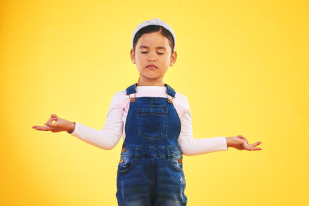 Lotus, hands and girl child with meditation in studio for wellness, peace or balance on yellow background. Children, mental health and kid with yoga pose for energy training or holistic exerciseの写真素材