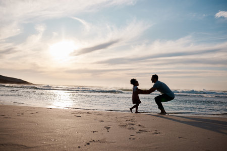Child is running to father, beach and silhouette, family with games and love, travel and freedom together outdoor. People, sunset and adventure, man and girl bonding with tropical holiday and natureの写真素材