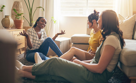 Happy, gossip and friends on a floor relax, talking and bond with advice in house together. Conversation, drama and women with diversity in a living room speaking, chilling and enjoy weekend freedomの写真素材