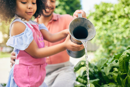 Gardening, father and daughter water plants, teaching and learning with growth in nature together. Backyard, sustainability and dad helping child watering vegetable garden with love, support and fun.の写真素材