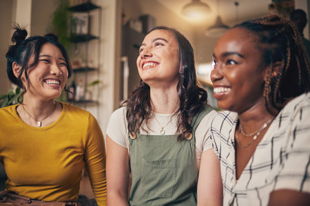 Happy, friends and women in a living room with funny, conversation and bond in their home together. Gossip, smile and people with diversity in a house for reunion, weekend and relax on day offの写真素材