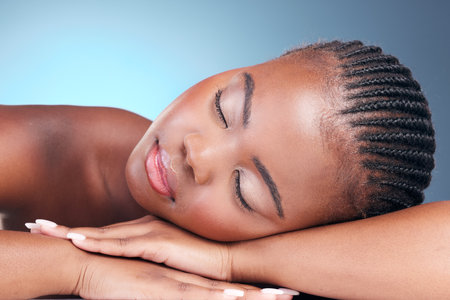 Skincare, relax and black woman in studio, sleeping and natural makeup with dermatology at luxury spa. Cosmetics, rest and dream facial beauty treatment with self care on blue background in Africa.の写真素材
