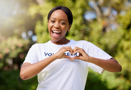 Heart, hands and portrait of volunteer woman with sign for care, support and charity outdoor in nature, forest or environment. Show, love and happy person volunteering in community service in empathyの写真素材