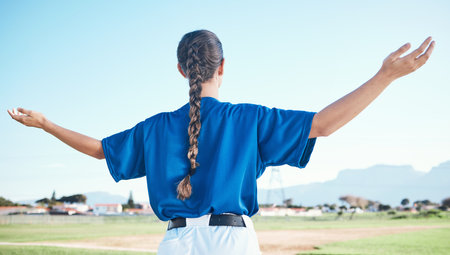 Woman, arms raised and winner with cheers, softball and sports with athlete on outdoor pitch and back view. Pray, hope and freedom, celebration and exercise, baseball player and winning competitionの写真素材