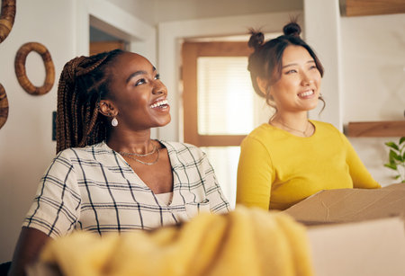 Happy, smile and lesbian couple moving in their new home with cardboard boxes together in living room. Happiness, love and interracial lgbtq women homeowners in the lounge of their modern apartment.の写真素材