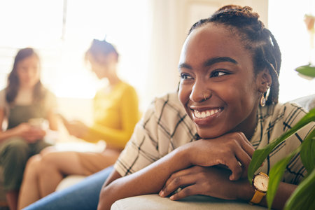 Happy, thinking and black woman relaxing in the living room with her friends in modern apartment. Happiness, positive and young African female person dreaming and sitting in lounge for rest at home.の写真素材