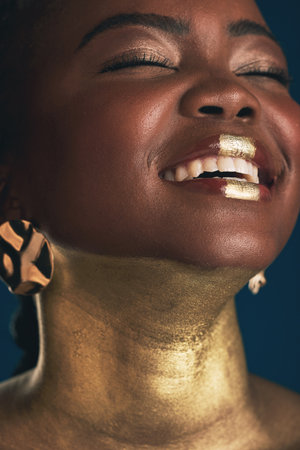 Smile, gold and makeup with face of black woman in studio for creative, luxury and cosmetics. Glow, glamour art and beauty with model on dark background for elegant, skincare and salon treatmentの写真素材