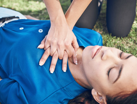 CPR, lungs press and woman hands on heart on sport, fitness and game field with accident and emergency. Training, paramedic and medical help for breathe from injury with first aid and athlete outdoorの写真素材