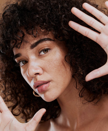 Frame, woman and face portrait for beauty, skincare and health or wellness of a latino female. Hand, gesture and skin care, facial health or wellbeing of a hispanic girl with smooth, soft skinの写真素材