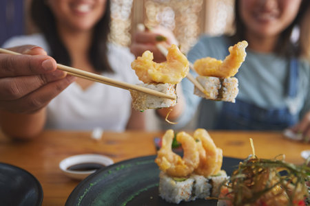Chopsticks, woman hands and shrimp sushi closeup at a table with Japanese cuisine food at restaurant. Young women, eating and tempura prawn with fish for lunch and meal on a plate with a smileの写真素材