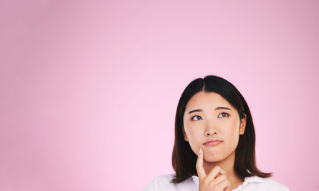 Asian woman, thinking and mockup space in solution, memory or ideas against a pink studio background. Female person in problem solving, reminder or plan emoji in decision or brainstorming on mock upの写真素材