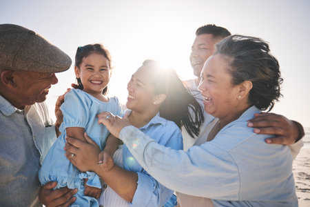 Family, smile and a girl on the beach with her grandparents in summer for holiday or vacation together. Love, sunset or flare with parents, kids and senior people by the ocean or sea for bondingの写真素材