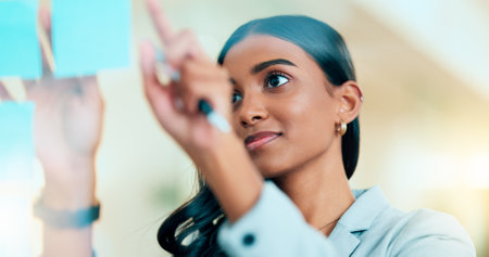 A smart female entrepreneur planning the strategy of her company in the office. Young confident and successful business woman leader thinking and working on a project at the workplaceの写真素材