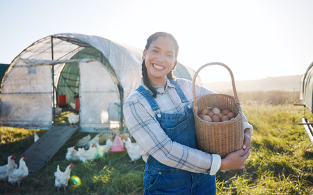 Happy woman with eggs in basket, farm and chickens on grass in sunshine countryside field with sustainable business. Agriculture, poultry farming and farmer holding produce for food, nature and birdsの写真素材