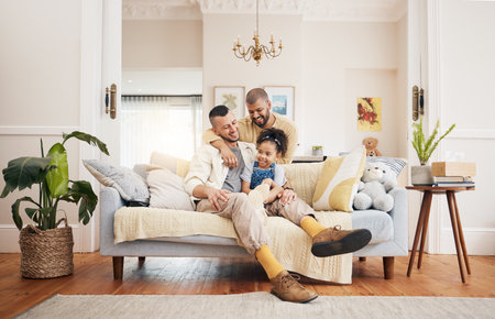 Gay, happy family and a child on a sofa at home with love, care and safety in a lounge. Lgbtq men, adoption and parents with a foster girl kid together on a couch for happiness, bonding and to relaxの写真素材