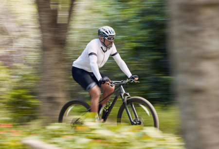 Freedom, fitness and man cycling in forest with energy, training or nature, workout and off road race. Speed, workout and cyclist on mountain bike for extreme sports, adrenaline or power performanceの写真素材