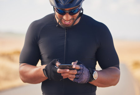 Phone, cycling and nature, happy man at rest stop in countryside looking at direction or map information online. Mobile chat, fitness app and smartphone, cyclist in road on internet search with smileの写真素材