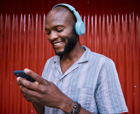 Black man, smartphone and headphones, smile with technology and listening to music or podcast....