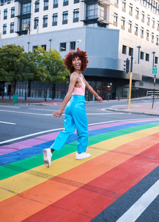 Happy, walking and a woman on a pride street for a celebration of freedom of love. Smile, city and a girl or person in support of lgbt community on a rainbow road for equality, excited and identityの写真素材