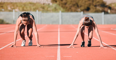 Woman, running and start in sports competition, race or fitness on outdoor stadium track together. Female person or people in preparation for run, marathon or sprint in team practice or trainingの写真素材