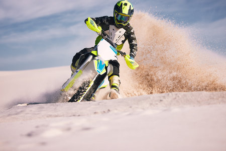 Motorcycle, dust and energy with a sports man riding a vehicle in the desert for adventure or...