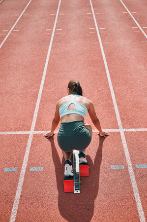 Start, running and fast with woman on race track for sports, competition and marathon. Exercise, health and wellness with runner training in stadium for challenge, speed and energy performanceの写真素材