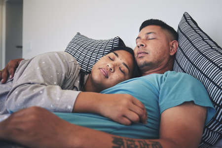 Couple, sleeping and hug together in bed to relax, rest and cuddle in marriage, relationship or love for partner in morning. Tired, man and woman dreaming with peace in home, house or bedroomの写真素材