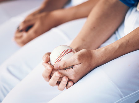 Hands, sports and baseball with a player in a dugout, waiting during a game of competition closeup. Ball, ready and uniform with an athlete holding equipment for a match in a stadium or venueの写真素材