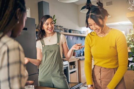 Conversation, bonding and girl friends in the kitchen of their new apartment having fun together. Happy, smile and group of young women talking and cooking a meal for lunch or dinner in a modern homeの写真素材