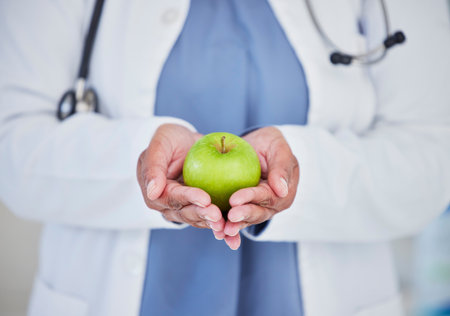 Doctor, hands and apple in healthcare diet, natural nutrition or healthy vitamin food at the hospital. Closeup of medical professional holding organic green fruit for health and wellness at clinicの写真素材