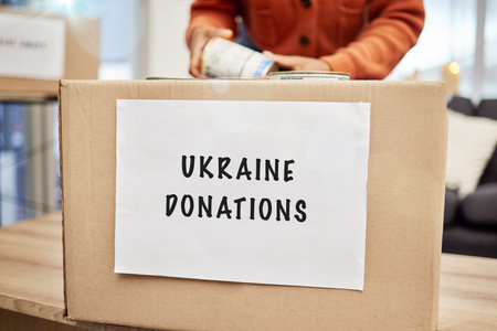 Box, donation and charity to support Ukraine with empathy, kindness and love for human rights, food or gift. Person, volunteer and hands with product, cardboard package and care for war victimsの写真素材