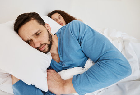 Divorce, fight and angry couple in bed after fight, discussion or frustrated by cheating wife at home. Bedroom, problem and man ignore annoyed woman with depression, anxiety or erectile dysfunctionの写真素材