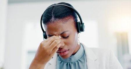 Black woman, call center and headache in stress, burnout or anxiety from strain at the office. African American female consultant suffering head pain, ache or sore eyes feeling overworked or stressedの写真素材