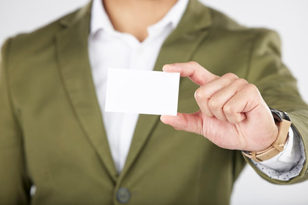 Man, hand and business card in advertising, marketing or branding against a white studio background. Closeup of businessman with paper, poster or sign for contact information or services on mockupの写真素材