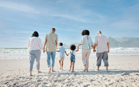 Family, holding hands and relax outdoor on a beach with love, care and happiness for summer vacation. Behind, space in sky or travel with men, women and children together at sea for holiday adventureの写真素材