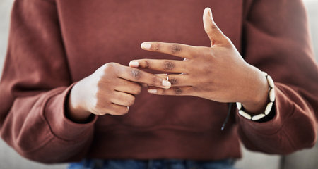 Wedding ring, hands and woman with divorce, decision and relationship doubt in her home. Jewelry, finger and female with marriage anxiety, commitment or fail in living room for choice regret in houseの写真素材